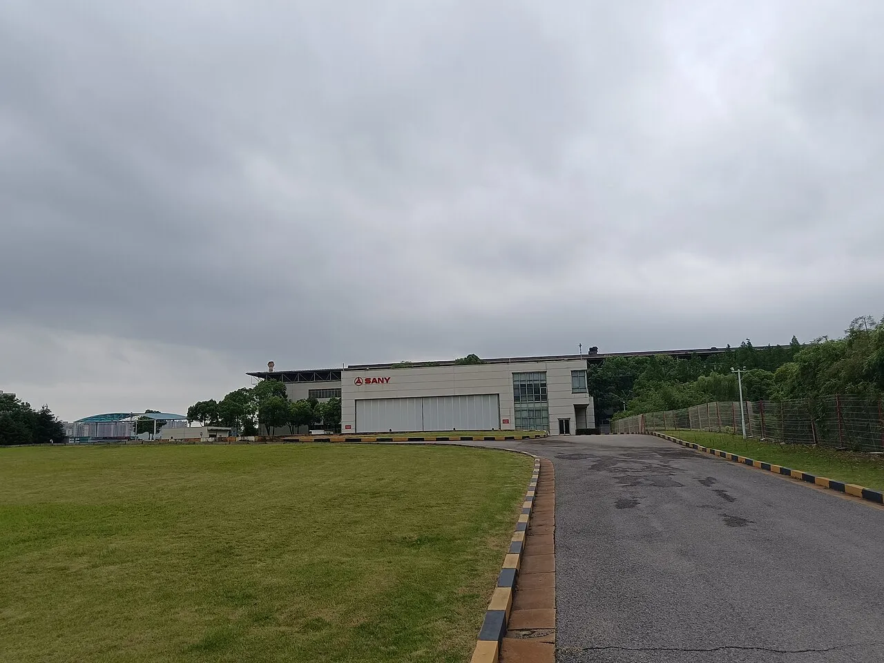 Industrial building with SANY signage, an access road and a lawn.