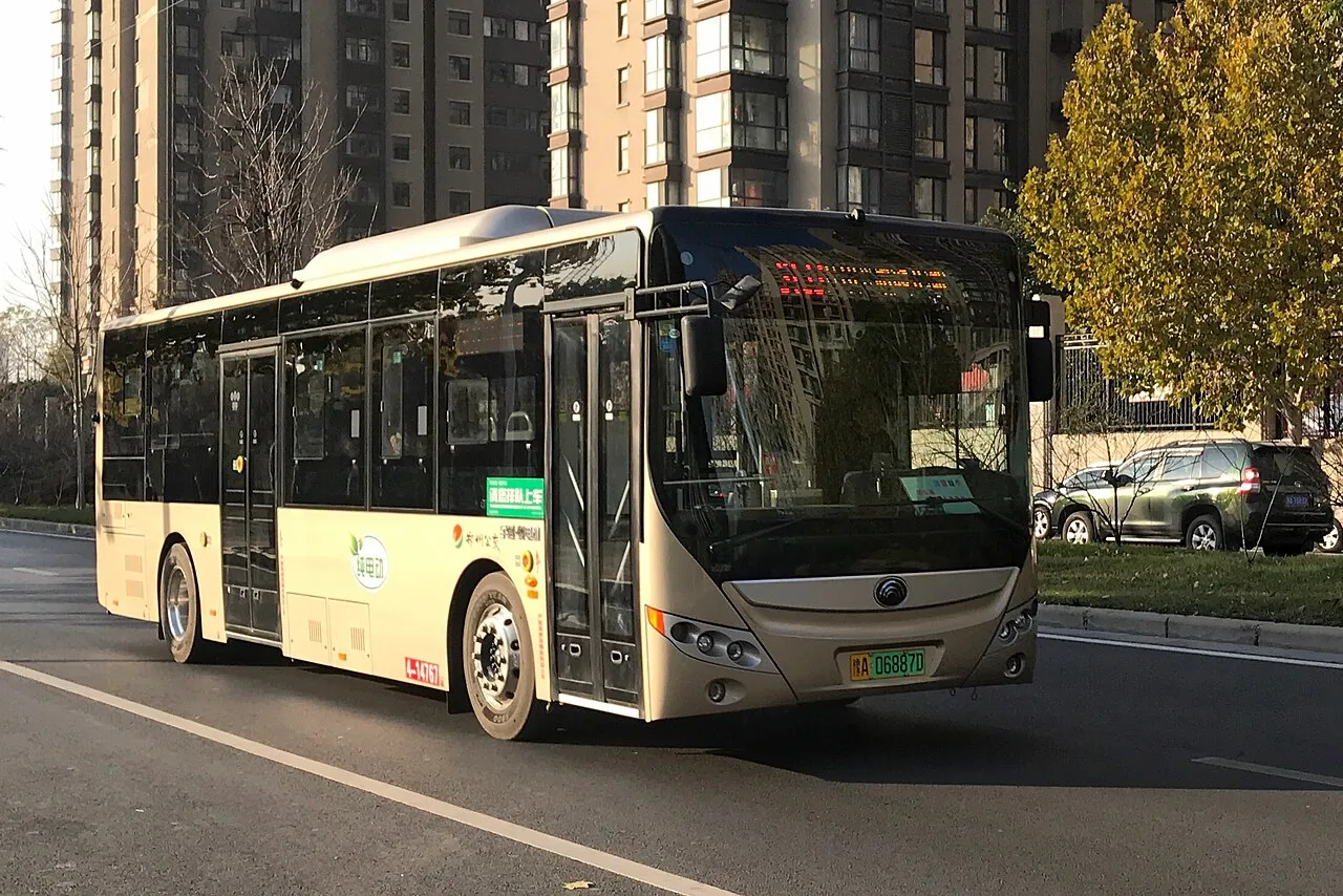 Electric bus on a city street with residential buildings in the background.