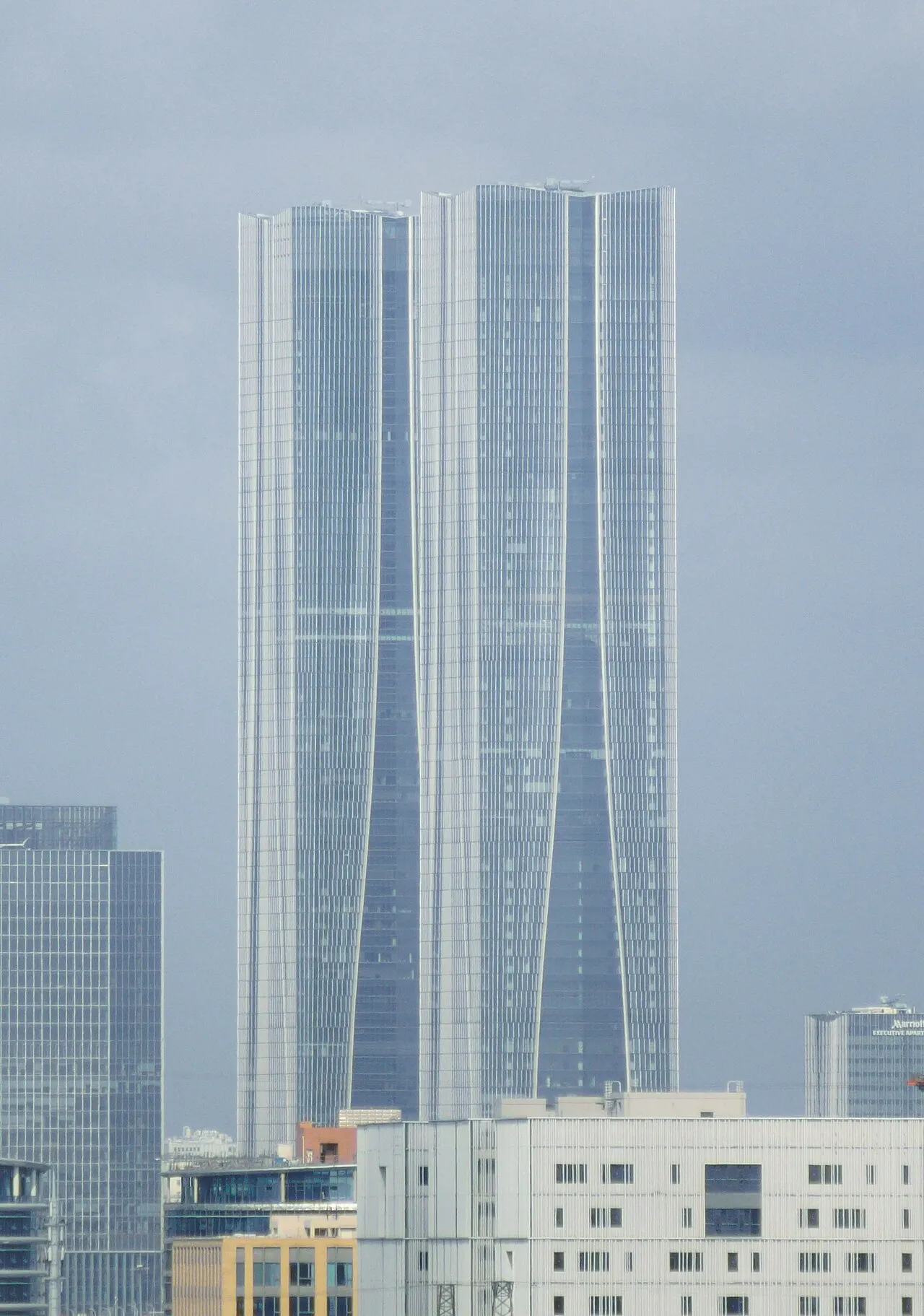 Two tall, connected towers behind lower buildings.