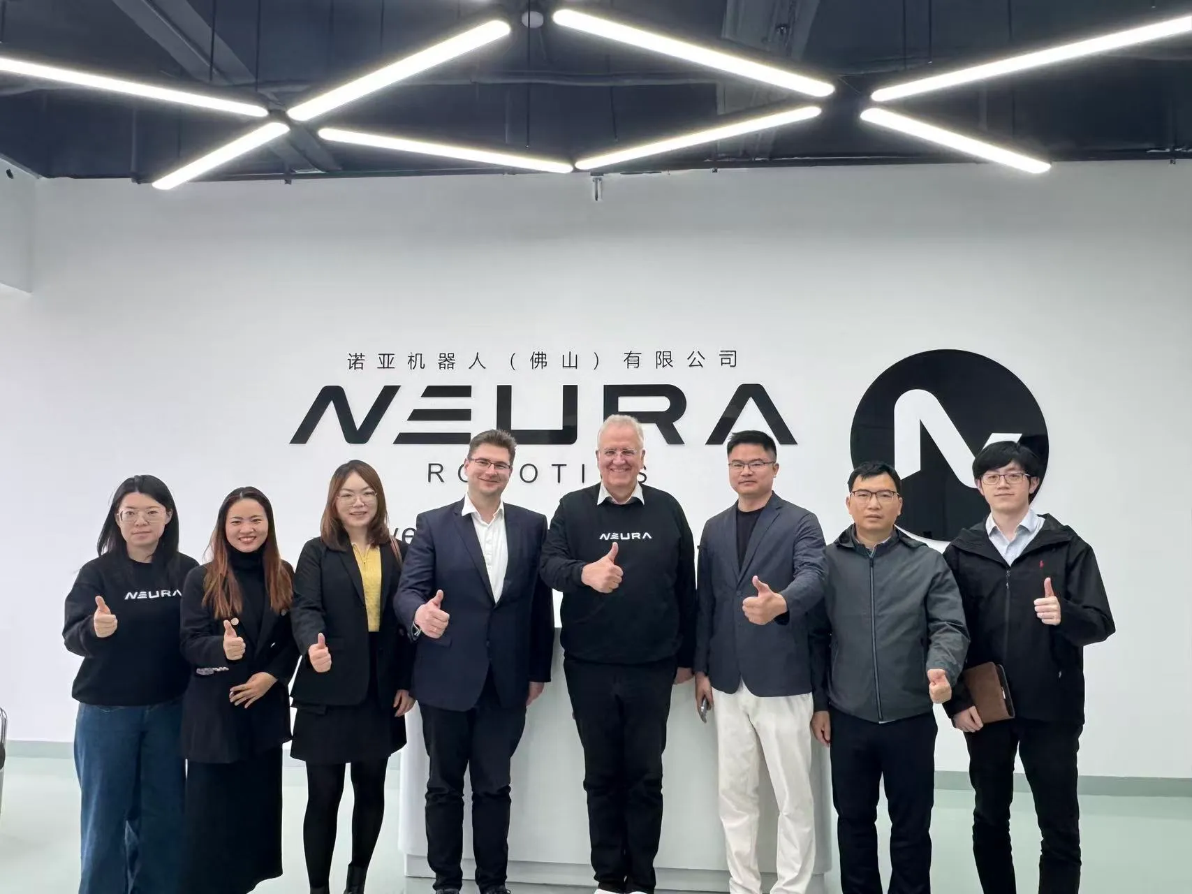 Besuchergruppe vor einem NEURA-Schriftzug