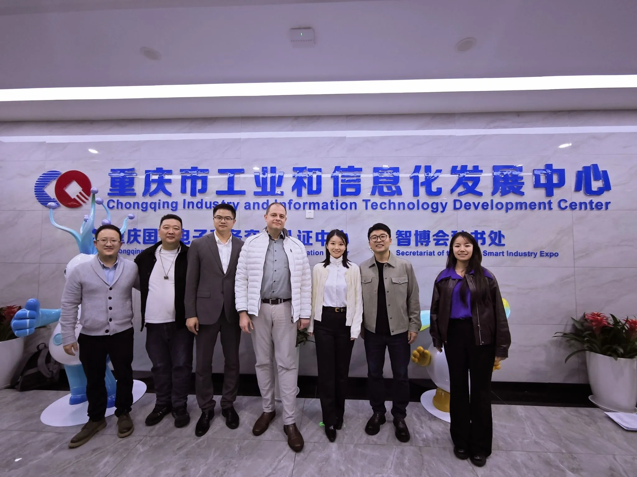 Besuchergruppe vor der Beschilderung des Chongqing Industrial and Information Development Center
