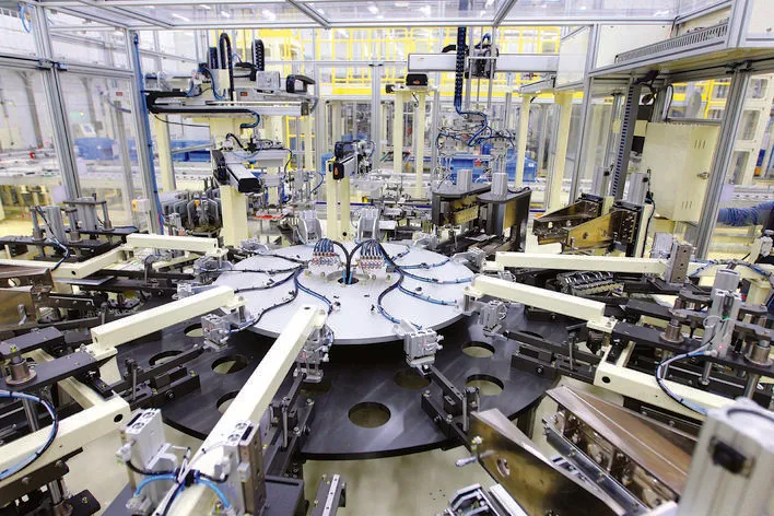 Automated battery manufacturing equipment inside a brightly lit production hall.