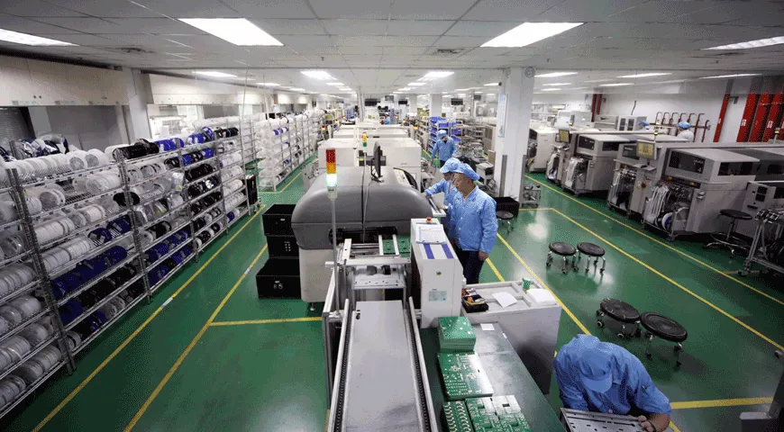 Electronics production with component reels, machinery and staff in blue protective clothing.